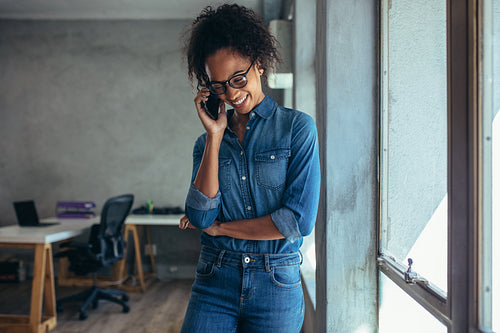 Positive woman in office talking on phone