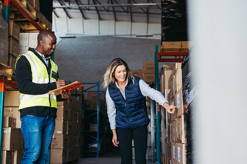 Happy warehouse workers taking inventory with a clipboard