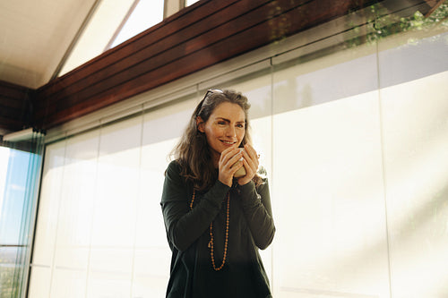 Cheerful senior woman sipping on a cup of tea at home