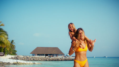 Joyful mother and child playing together on a pristine beach during a luxury family vacation