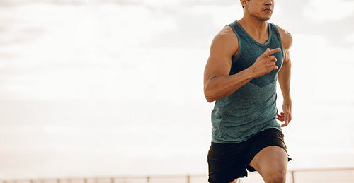 Young man running along a seaside promenade