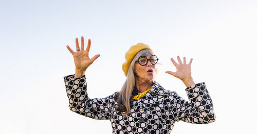 Senior woman lifting her hands playfully outdoors