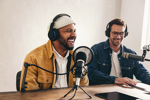 Happy radio presenter speaking into a microphone in a studio