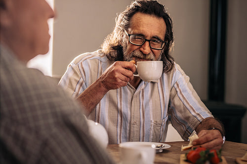 Retired man sitting with friend having tea