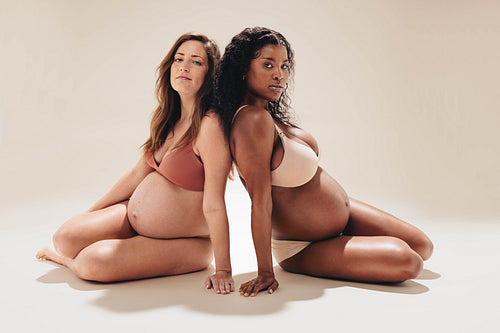 Two pregnant women wearing underwear in a maternity photoshoot