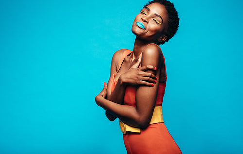 Woman with vivid makeup hugging herself