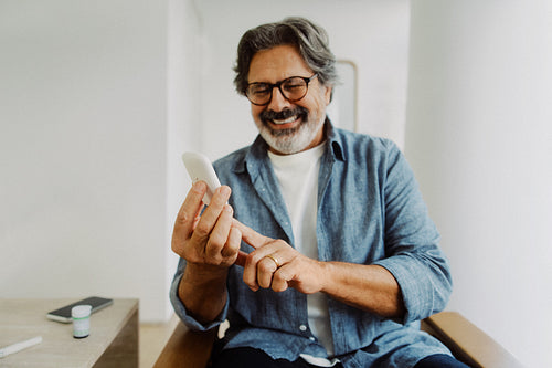 Senior man checks glucose meter at home