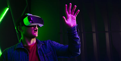 Young man playing an amazing game in virtual reality, wearing a VR headset and interacting with his hands