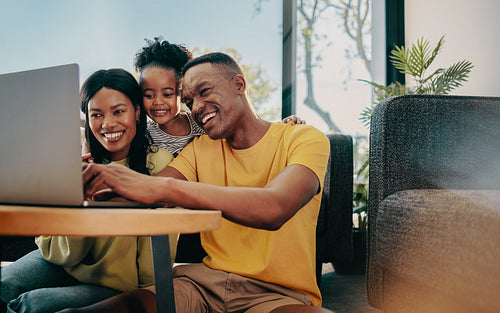 Searching for the perfect family movie, happy family of three browses a laptop at home