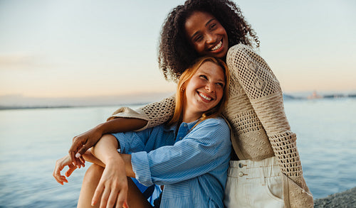 Two friends sharing a joyful moment by the beach at sunset