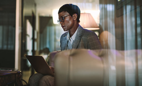 Female on business trip using laptop in hotel lobby