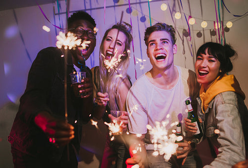 Group of friends celebrating with party sparklers and confetti
