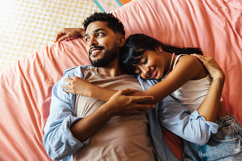 Happy father and daughter embracing on a cozy pink bedspread