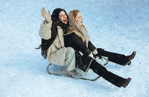 Women sledding and laughing together in snow