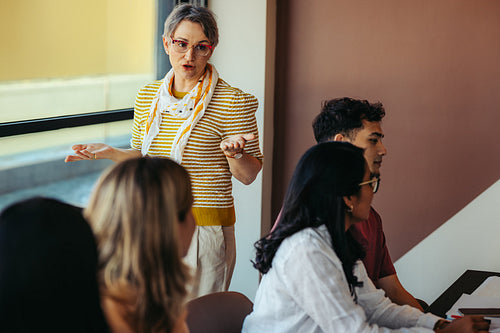 Mature female educator leading a classroom discussion with engaged students learning in a progressive learning environment
