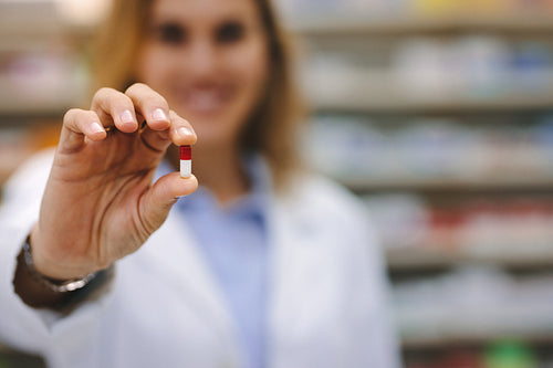Female pharmacist holding a medicine capsule
