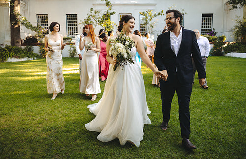 Bride and groom walking joyfully surrounded by guests on wedding day