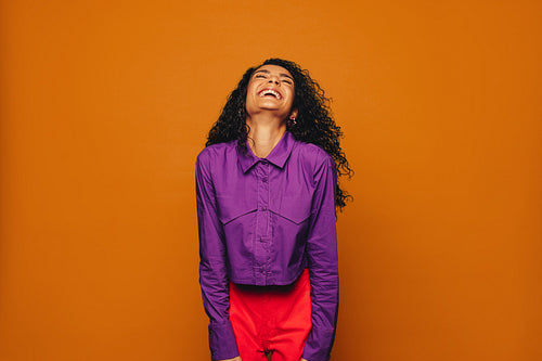Joyful woman celebrating life in vibrant colourful style on orange background