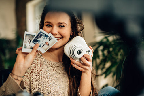 Happy female blogger showing instant photographs on camera