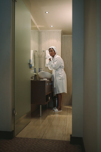 Woman wiping her face with towel in bathroom
