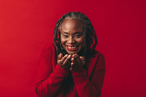 Mature woman blowing air confetti in a studio