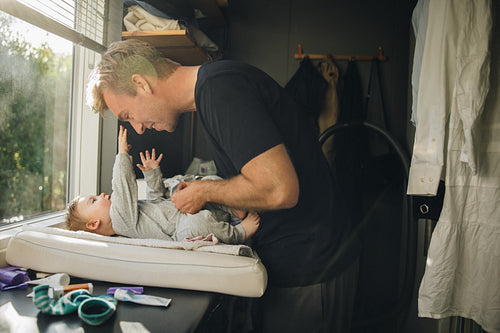 Caring father changing baby diaper at home