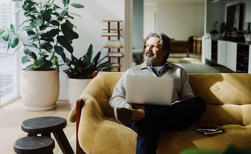 Senior man browses online on a laptop at home