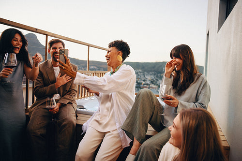 Friends enjoying an evening balcony gathering with drinks and laughter
