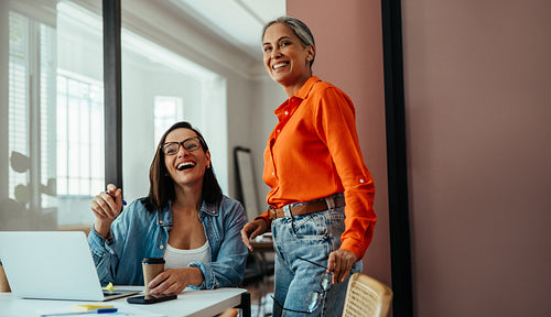Businesswomen colleagues enjoying coffee in a modern colorful office setting