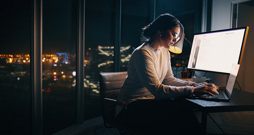 Late night work: Busy businesswoman typing on laptop at office desk