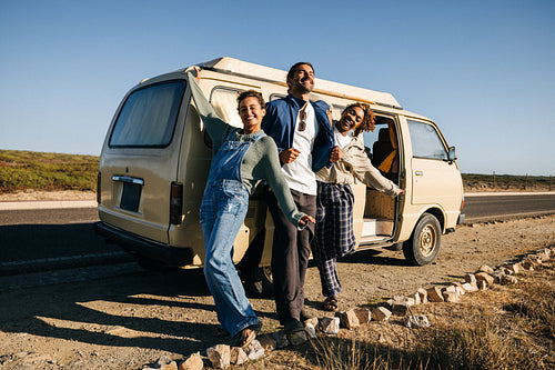 Posing in the sun: Friends stand proudly beside their camper van