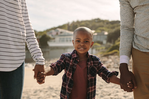 Boy walking with his parents on beach