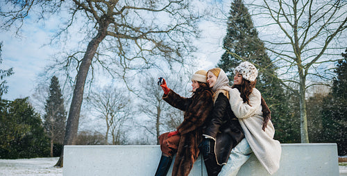 Women take a selfie while sitting in a winter park