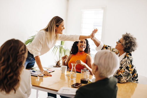 Business colleagues high fiving each other in a boardroom