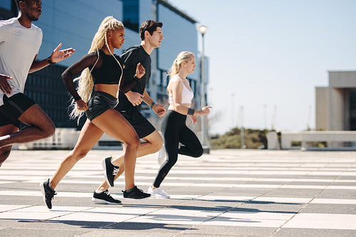 Multi-ethnic group of people running together in the city