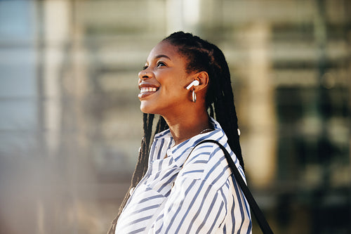 Cheerful young business woman smiling happily while walking outdoors in the city