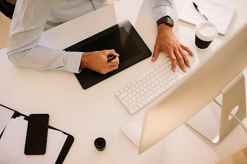 Top view of man using digitizer to write text in computer