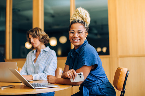 Two young women working and smiling in a bright, professional environment