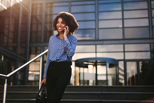 Businesswoman walking outdoors talking on cell phone