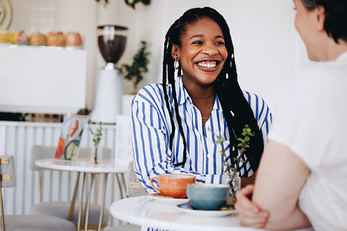 Happy young businesswoman having a coffee meeting with a colleague in a cafe
