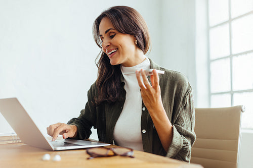 Happy business woman using a laptop and speaking on the phone