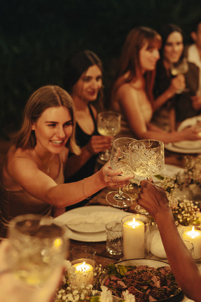 Outdoor dinner party with friends celebrating and toasting by candlelight