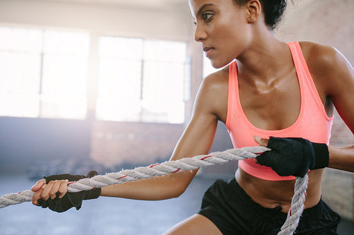 Fit young woman exercising with rope at a gym