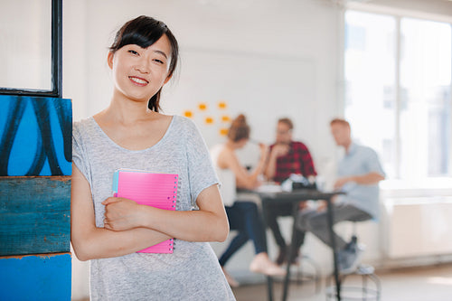 Smiling young asian woman standing in office