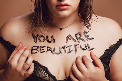Plus size woman with "you are beautiful" written on her body