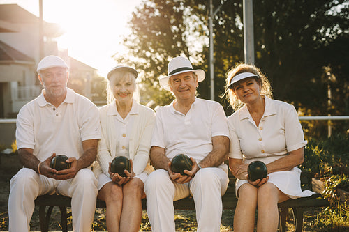 Senior friends sitting outdoors with boules in hand
