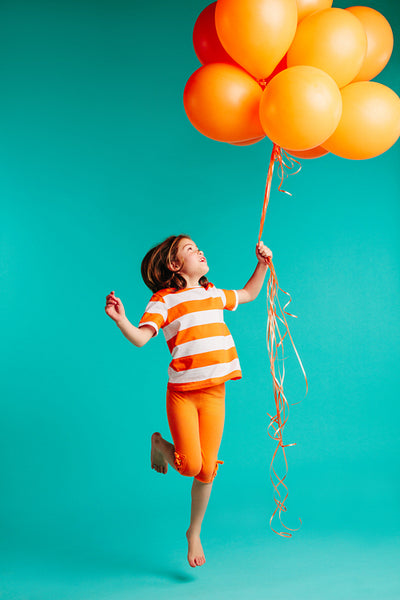 Happy girl jumping with orange balloons