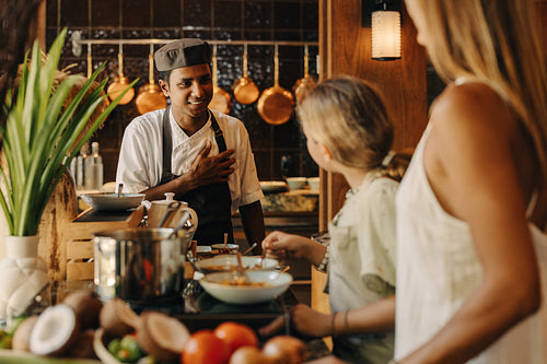 Chef interacting with customers in a warm and welcoming kitchen environment
