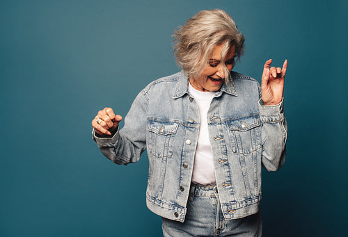 Joyful older woman freestyling on a blue denim background