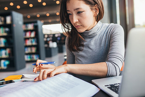Young woman studying on a book and taking notes